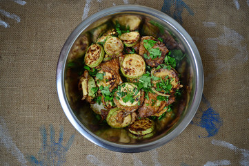 fried zucchini in a plate on a background of burlap.Top view