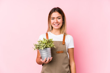 Young caucasian gardener woman in a pink background happy, smiling and cheerful.