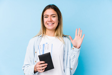 Young caucasian woman holding a passport isolated smiling cheerful showing number five with fingers.