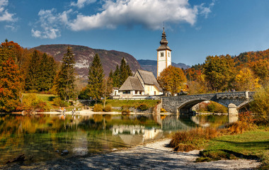 Obraz premium Amazing nature landscape. Bohinj Lake, Church of St John the Baptist with bridge. Triglav National Park, Julian Alps, Slovenia. Colorful summer panorama. Wonderful sunny scenery