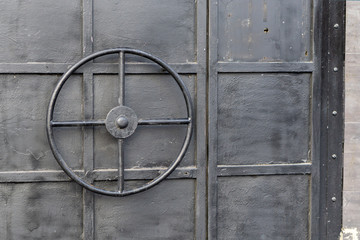 wheel-shaped handle on a black iron door