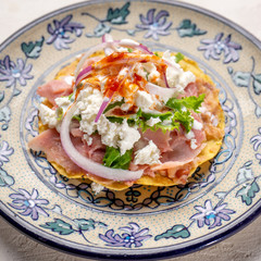 Mexican ham toast also called tostadas with beans and cheese on white background