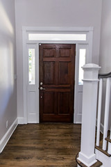 Solid wood dark stained front door in a home with vaulted ceilings and transom windows - obrazy, fototapety, plakaty