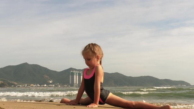 Girl doing rhythmic gymnastics on the seashore at sunrise