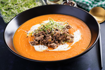 Delicious cream of pumpkin soup with roasted forcemeat made of beef minced meat in a bowl on a dark table. Thanksgiving Day.