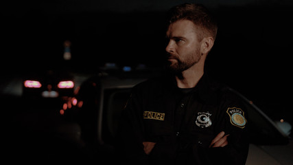 Attractive severe man with beard policeman in uniform with arms crossed looking on camera with...