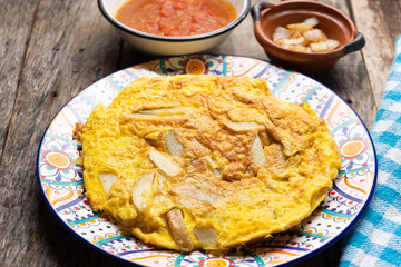 Spanish scrambled eggs with potatoes called tortilla or tapa on wooden background