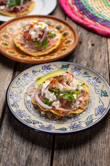 Mexican ham toast also called tostadas with beans and cheese on wooden background