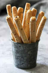 Traditional italian breadsticks grissini with flax seeds on a gray background.