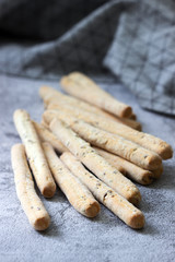 Traditional italian breadsticks grissini with flax seeds on a gray background.