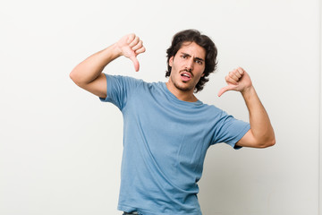 Naklejka premium Young handsome man against a white background showing thumb down and expressing dislike.