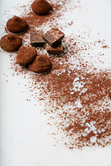 Chocolate candy truffles and chocolate pieces sprinkled with cocoa dust and sea salt over the marble background. Tasty confectionery collection. Selective focus