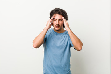 Fototapeta premium Young handsome man against a white background touching temples and having headache.