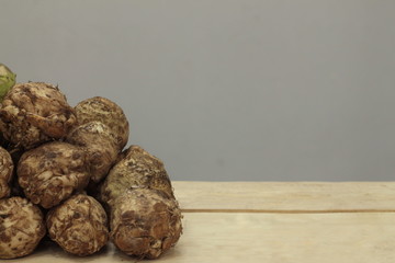 A large pile of roots of brown celery lies on a counter in a store.