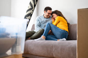 Obraz premium Happy couple cuddle in couch and celebrating moving to new home