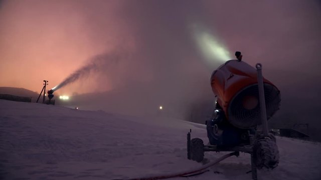 Snow making system. A snow cannon sprays water and makes snow. On sunrise, the camera moves around the snow cannon and creates a parallax effect. A lantern shines in the background.