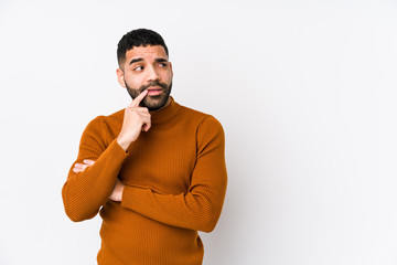 Young latin man against a white background isolated relaxed thinking about something looking at a copy space.