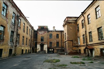Fototapeta na wymiar Sullen desolate yard with abandoned old red brick buildings in St.Petersburg, Russia