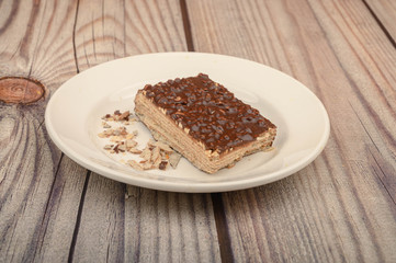 A piece of waffle cake on a white plate on a wooden background. Close up.
