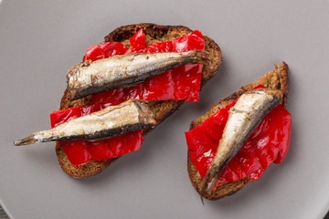 Fish sandwiches with sprats. Sandwich with red bell pepper and sprats on a gray plate. A set of...