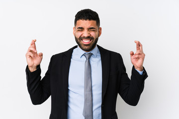 Young latin business woman against a white background isolated crossing fingers for having luck