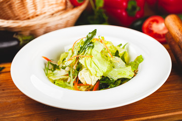 Fresh mixed green salad with carrot on white plate.