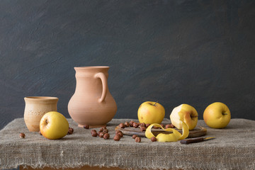 Still life in rustic style. A set of pottery, apples and hazelnuts on the table.  Natural light...