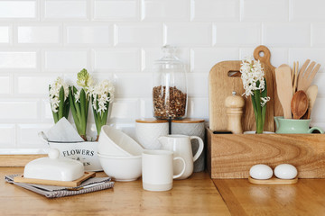 Kitchen utensils and dishware spring flowers on wooden table.