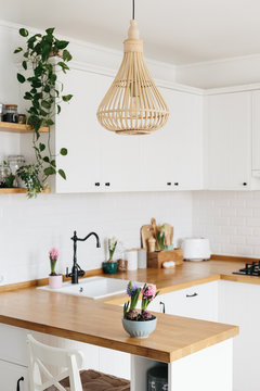 Modern white u-shaped kitchen in scandinavian style. Spring decoration spring flowers