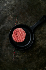 Raw Ground beef meat Burger steak cutlets with seasoning served on metal frying pan over rustic metal background. Top view