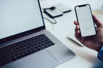 Crop businessman with smartphone and laptop