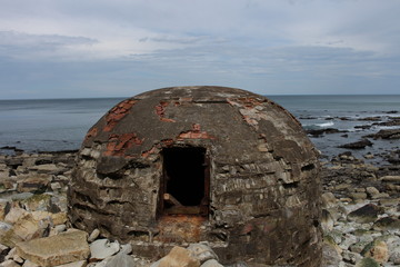 bunker militar de costa en una playa de rocas nudista del norte de España con cielo nublado