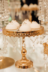 Sweet cakes on a buffet table. Delicious candy bar with cake pops. White and gold style, beautiful design.