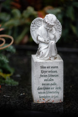Figur mit Engel auf einem Grab mit Text "Wenn wir unseren Körper verlassen, frei von Schmerzen und allem, was uns quälte, dann können wir leicht wie ein Schmetterling heimkehren zu Gott"