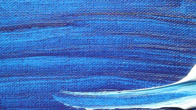 Painting the canvas with a bright blue paint brush close up