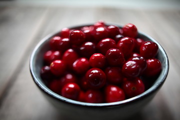 fresh cranberries in a  bowl on wooden background 