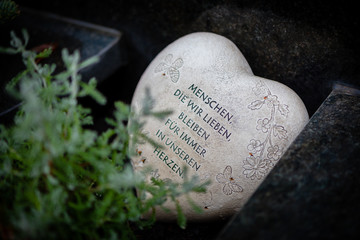 Stein auf Grab mit Text "Menschen, die wir lieben, bleiben für immer in unseren Herzen"