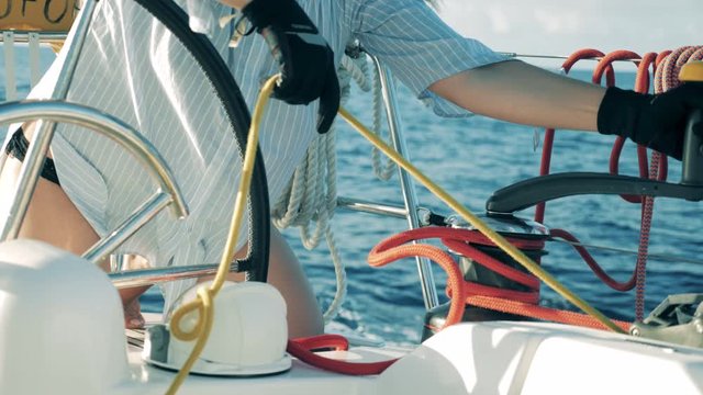 Ropes onboard of a yacht are getting unreeled by a woman