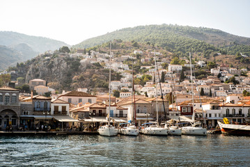 Fototapeta premium View of Hydra, Greece seaside town with hills, building and sailboats