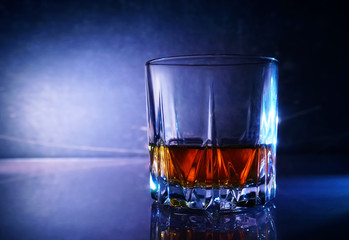 Whiskey glass with alcohol on dark background