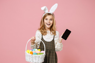 Little blonde kid girl 11-12 years old in spring dress bunny rabbit ears hold in hand cell phone...