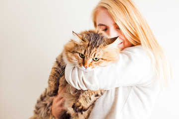 Happy woman holding siberian cat and kissing him