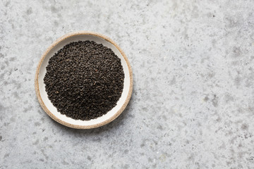 Basil or grain seeds in bowl isolated on grey background. Scientific name is Ocimum x citriodorum. Top view, space for text.