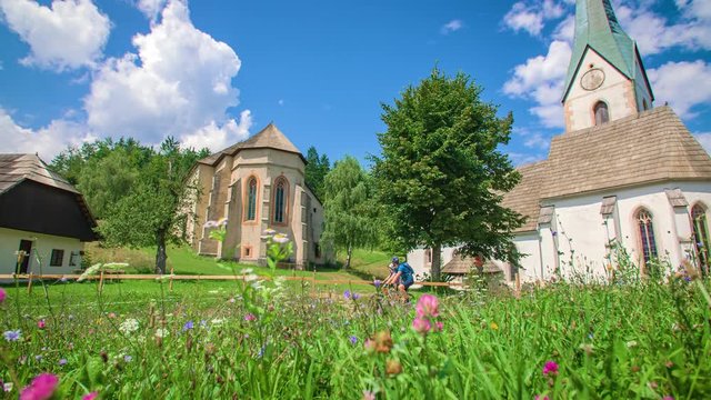 Young sports couple exploring Koroska region with e bikes, driving by churches in Lese, Slovenia