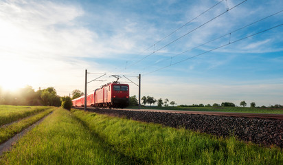 Red train traveling in a summer landscape. Train in nature