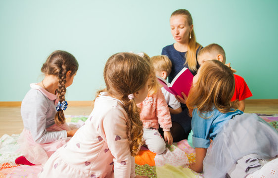 Young teacher reading to kids a faity tale