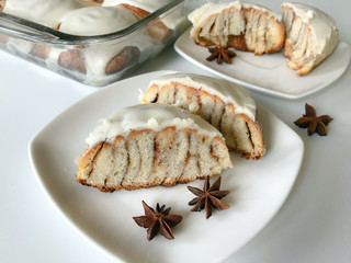 Cinnabons on a plate. One is cut in half, layers of baked bun are visible. Next to decorate cinnamon stars.