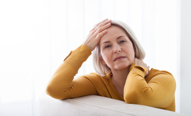 Woman suffering from stress or a headache grimacing in pain as she holds the back of her neck with...