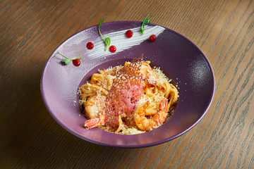 Traditional italian linguine pasta with shrimp and parmesan in a purple ceramic plate. Close up view. Film effect during post. Soft focus