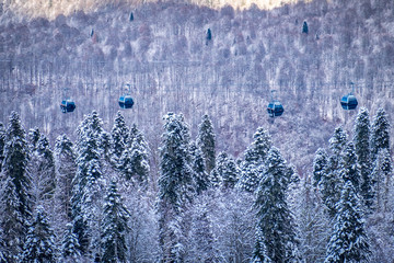 Winter Mountain landscape at the Rosa Khutor ski resort in Sochi, Russia. Cable car cabin over pine...